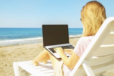 Laptop vasıl belgili tanımlık kıyı güneşli günde çalışan genç sarı saçlı kadın. Kadın el yazarak beyaz dizüstü bilgisayar laptop, bloglama, copywriting kapatın. Yakın çekim, alanı Kopyala.