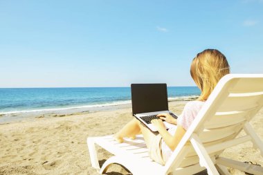 Laptop vasıl belgili tanımlık kıyı güneşli günde çalışan genç sarı saçlı kadın. Kadın el yazarak beyaz dizüstü bilgisayar laptop, bloglama, copywriting kapatın. Yakın çekim, alanı Kopyala.