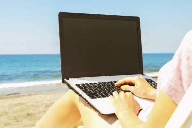 Laptop vasıl belgili tanımlık kıyı güneşli günde çalışan genç sarı saçlı kadın. Kadın el yazarak beyaz dizüstü bilgisayar laptop, bloglama, copywriting kapatın. Yakın çekim, alanı Kopyala.
