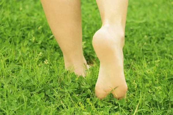 Weibliche nackte Füße auf aufgemähtem Rasengras. Eine junge Frau, die sich barfuß im Freien ausruht, macht eine Pause. Student auf dem Campus des College. — Stockfoto