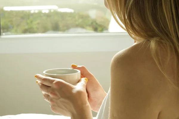 Gran habitación espaciosa de hotel llena de luz solar y rayos de sol. Comienzo optimista del día. Mujer rubia ropa de casa acogedora bienvenida a la luz del día por la mañana. Nuevo día nuevo concepto de mí . — Foto de Stock