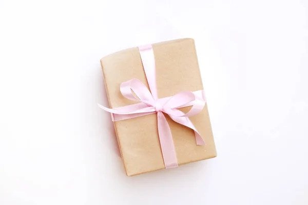 Rustika komposition med vackra närvarande i craft papper omslag. Närbild på födelsedagspresent i brun sjal med band och rosett. — Stockfoto
