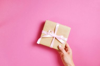 Doğum günü hediyesi vintage craft kağıt ambalaj içinde tutan eller, yakın çekim. Şimdiki zamanda kadının kolları ile Femenine kompozisyon.