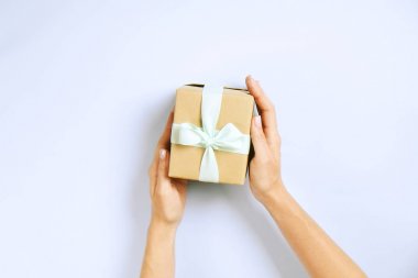 Doğum günü hediyesi vintage craft kağıt ambalaj içinde tutan eller, yakın çekim. Şimdiki zamanda kadının kolları ile Femenine kompozisyon.