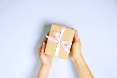 Doğum günü hediyesi vintage craft kağıt ambalaj içinde tutan eller, yakın çekim. Şimdiki zamanda kadının kolları ile Femenine kompozisyon.