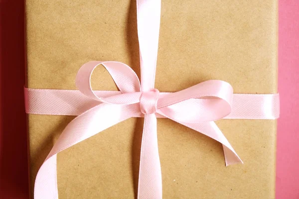 Rustika komposition med vackra närvarande i craft papper omslag. Närbild på födelsedagspresent i brun sjal med band och rosett. — Stockfoto