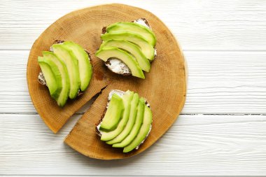Vejetaryen sandviç, çavdar ekmeği tost, avokado, vegenaise eggless mayonez sos, baharat, Beyaz ahşap doku tablo susam. Vejetaryen beslenme. Ulusal avokado gün kavramı. Yakın çekim, arka plan
