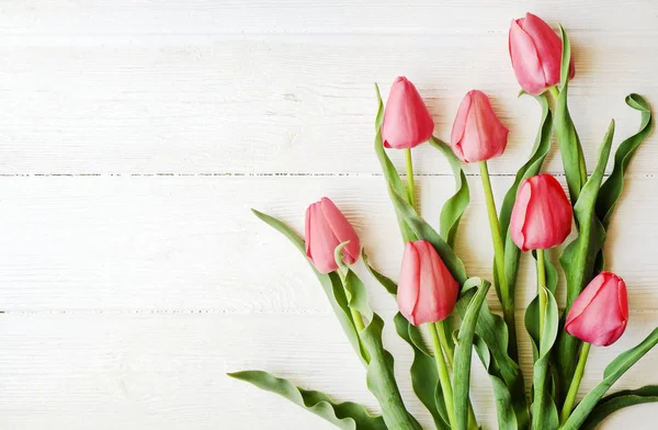 Bunch of pink tulip in beautiful spring holidays composition lying on white wooden textured table background. Mother's day bouquet arrangement. Flowers for women's day. Copy space, close up, top view. — Stock Photo, Image
