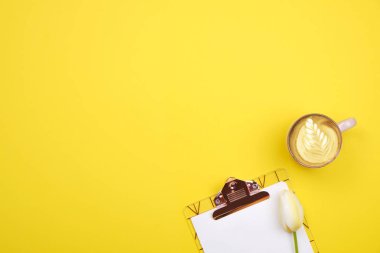 Sayfa boş Pano, kalem, kahve fincanı, Sarı zemin üzerine lale buketi ile kadınsı masaüstü oluşturma. Küçük kız işyeri, anneler günü için çiçek. Üstten Görünüm, düz yatıyordu, yakın çekim, alanı Kopyala.