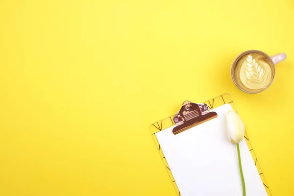 Composição do desktop feminino com área de transferência de folha em branco, lápis, xícara de café, buquê de tulipas no fundo amarelo. Local de trabalho feminino, flores para o dia da mãe. Vista superior, flat lay, close up, espaço de cópia . — Fotografia de Stock