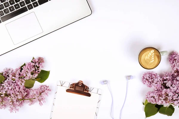 Draufsicht auf den Schreibtisch einer Arbeiterin mit Laptop, Blumen und verschiedenen Büroutensilien. feminine kreative Gestaltung. — Stockfoto