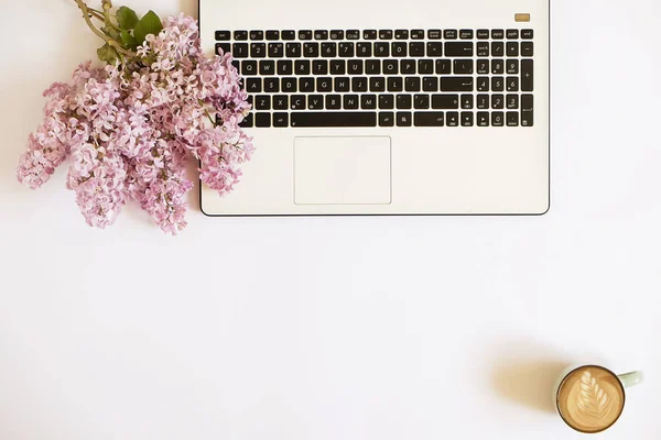 Draufsicht auf den Schreibtisch einer Arbeiterin mit Laptop, Blumen und verschiedenen Büroutensilien. feminine kreative Gestaltung. — Stockfoto