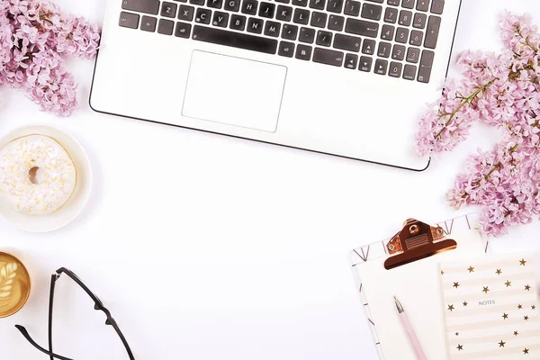 Draufsicht auf den Schreibtisch einer Arbeiterin mit Laptop, Blumen und verschiedenen Büroutensilien. feminine kreative Gestaltung. — Stockfoto