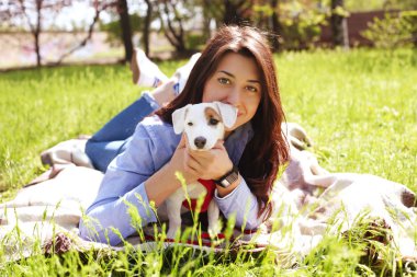 Portre sevimli sevmek çekici genç kadın jack russell terrier köpek park, yeşil çim, yeşillik arka plan. Hippi erkek güneş gözlüğü gülümseyen, çimenlerin üzerinde onu köpek evcil hayvan. Yakın çekim, alanı Kopyala.
