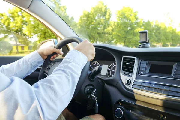 Autoinnenraum mit männlichem Fahrer am Steuer, weiches Sonnenuntergangslicht. luxuriöses Armaturenbrett und Elektronik. — Stockfoto