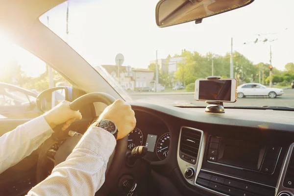 Autoinnenraum mit männlichem Fahrer am Steuer, weiches Sonnenuntergangslicht. luxuriöses Armaturenbrett und Elektronik. — Stockfoto