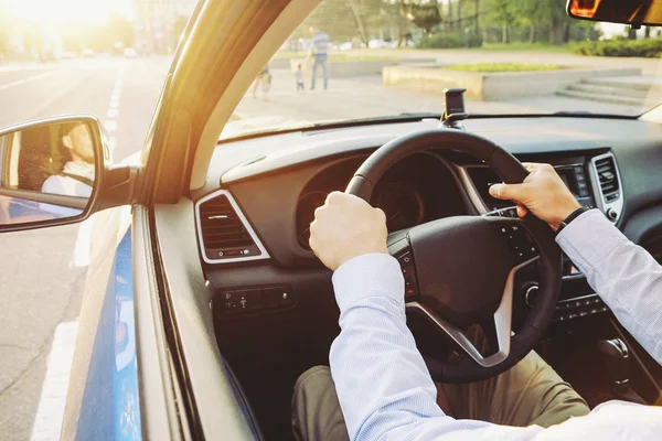 Autoinnenraum mit männlichem Fahrer am Steuer, weiches Sonnenuntergangslicht. luxuriöses Armaturenbrett und Elektronik. — Stockfoto