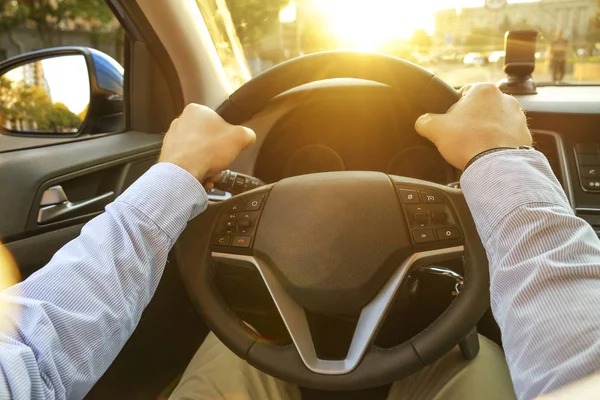 Autoinnenraum mit männlichem Fahrer am Steuer, weiches Sonnenuntergangslicht. luxuriöses Armaturenbrett und Elektronik. — Stockfoto