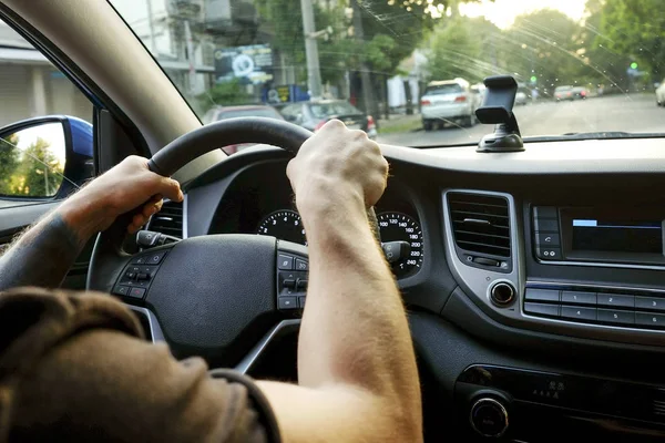 Autoinnenraum mit männlichem Fahrer am Steuer, weiches Sonnenuntergangslicht. luxuriöses Armaturenbrett und Elektronik. — Stockfoto