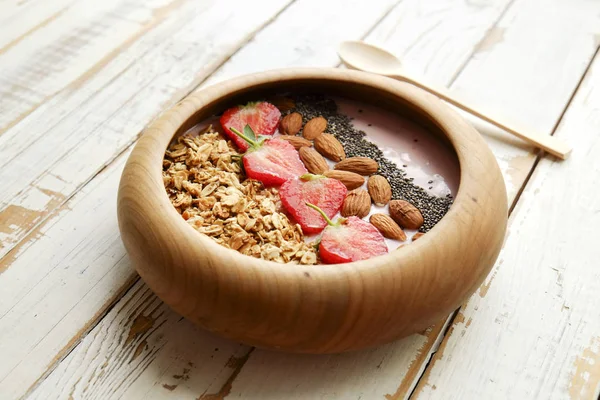 Wooden smoothie bowl, assorted ingredients on table. Healthy nutritious breakfast with vegan yogurt, raw fruits, nuts and cereals. — Stock Photo, Image