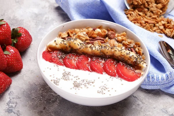 Tazón de batido de madera, ingredientes surtidos en la mesa. Desayuno nutritivo saludable con yogur vegano, frutas crudas, nueces y cereales . —  Fotos de Stock