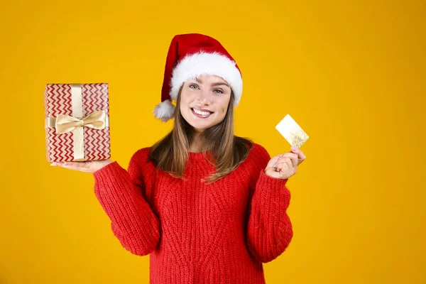 Happy woman in warm knitted sweater and beanie posing over yellow wall background. — Stock Photo, Image