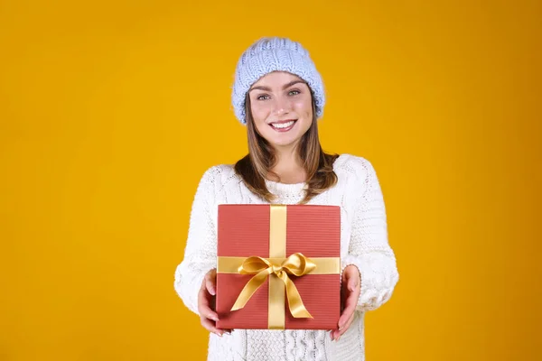 Happy woman in warm knitted sweater and beanie posing over yellow wall background. — Stock Photo, Image