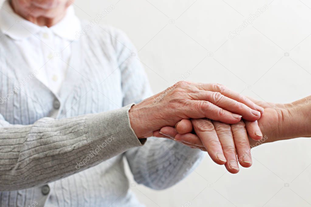 Close up shot of elderly woman's hands. Old lady wearing grey knitted cardigan.