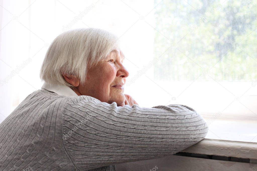 Portrait of sad and lonely elderly woman wearing grey cardigan.
