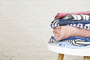 Deri kaplı duvar arkaplanının üzerine yığılmış farklı giysiler..