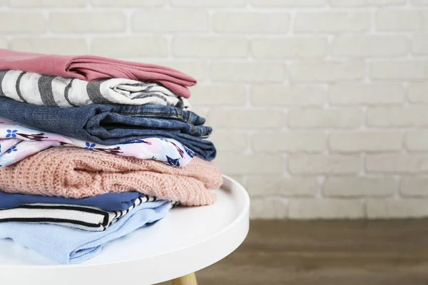Set of different clothing folded in stack over textured wall background.