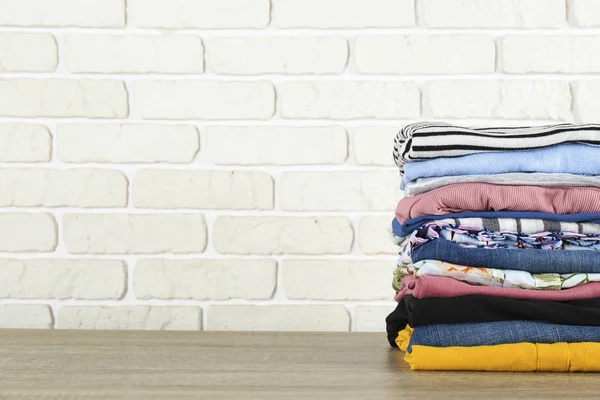 Set of different clothing folded in stack over textured wall background.