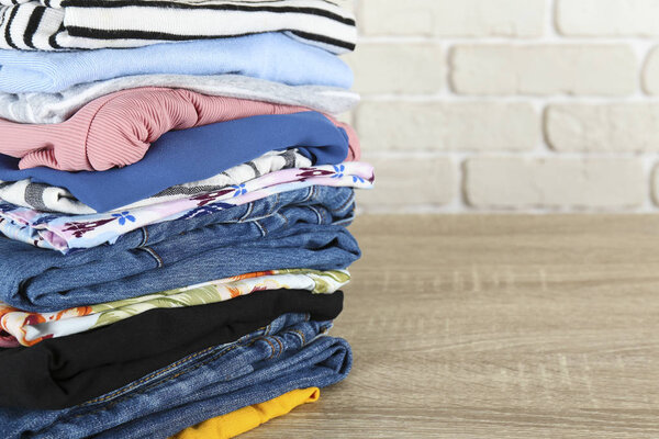 Set of different clothing folded in stack over textured wall background.