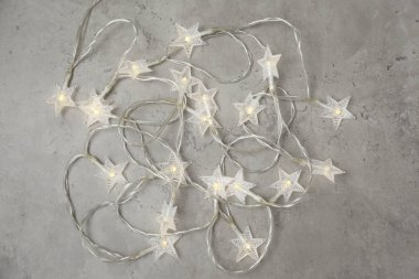 Noel konsepti. Yeni yıl dekorasyon yıldızı ışıkları şekillendirdi, grunge taşı masa üzerinde bir sürü küçük lamba bulunan çelenkler. Üst görünüm, düz görünüm, kopyalama alanı.