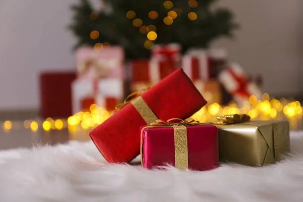 Pin de Noël traditionnel avec des décorations de vacances sur fond et une pile de cadeaux au premier plan. Les lumières de Bokeh brillent dans la soirée. Gros plan, espace de copie, fond, intérieur . — Photo