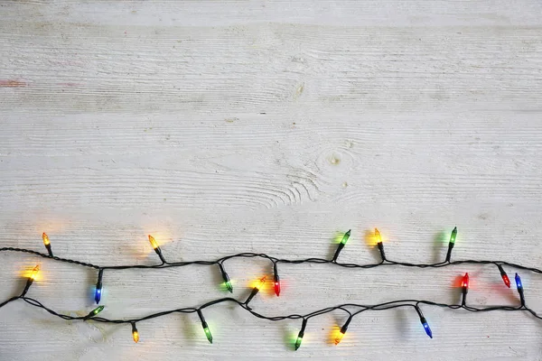 Concetto di sfondo natalizio. Le luci di decorazione di anno nuovo, la ghirlanda con molte piccole lampade di colore diverso brillano su tavolo di legno grunged grigio. Vista dall'alto, disposizione piatta, spazio di copia . — Foto Stock