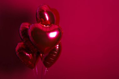 Kalp şeklinde helyum şişirilmiş kırmızı folyo hava balonu havada uçuşuyor..