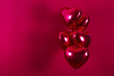 Kalp şeklinde helyum şişirilmiş kırmızı folyo hava balonu havada uçuşuyor..