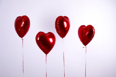 Kalp şeklinde helyum şişirilmiş kırmızı folyo hava balonu havada uçuşuyor..