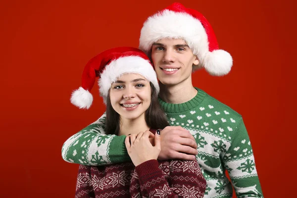 Пара молодих людей, одягнені в потворні різдвяні светри, позують на барвистому ізольованому фоні . — стокове фото