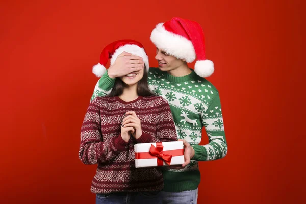 Un par de jóvenes vistiendo suéteres feos de Navidad, posando sobre un colorido fondo aislado . — Foto de Stock