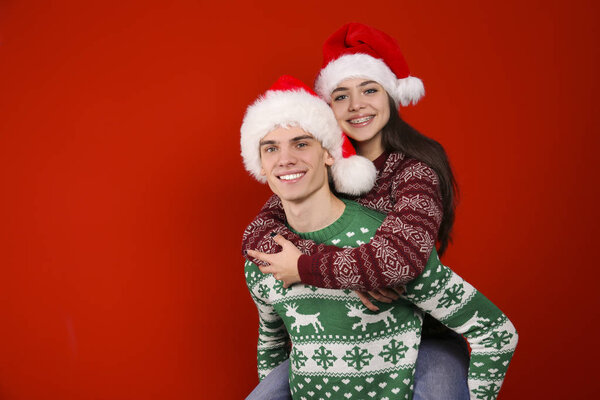 Couple of young people wearing ugly christmas sweaters, posing over colorful isolated background.