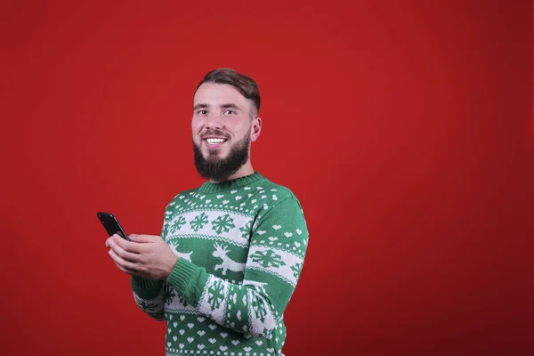 Молодий чоловік з ідеально дорослою бородою на різдвяному вбранні на фоні червоної стіни . — стокове фото