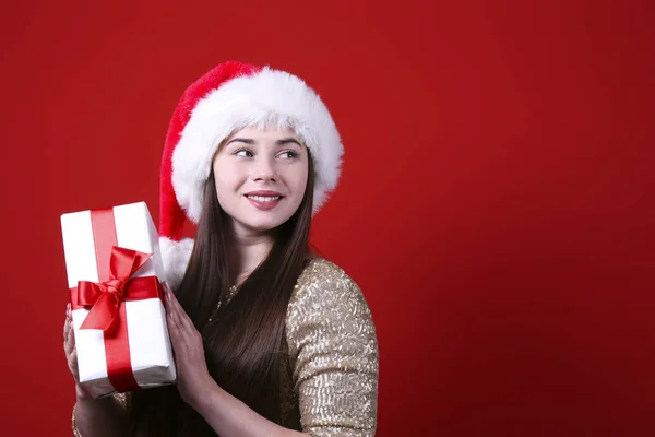Smiling woman wearing santa hat on red wall background. — Stock Photo, Image