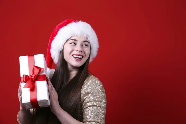 Smiling woman wearing santa hat on red wall background. — Stock Photo, Image