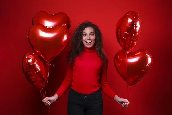 Preciosa joven posando sobre pared roja sosteniendo helio inflado globo . — Foto de Stock