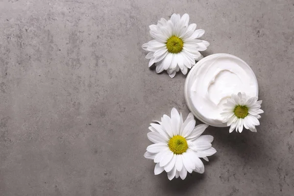 Fondo de textura de hormigón con tarro de crema y hermosa composición de flores . — Foto de Stock