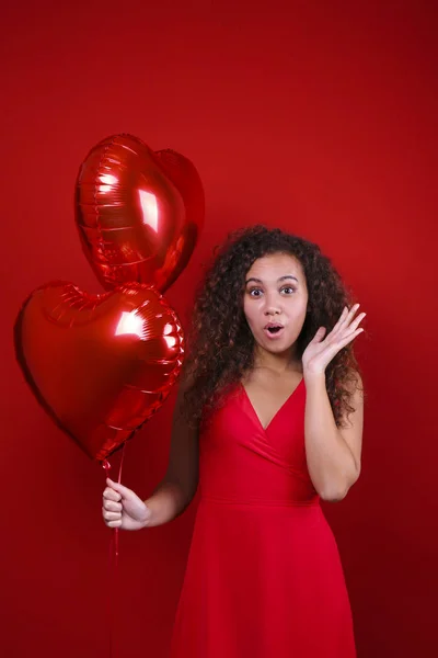 Preciosa joven posando sobre pared roja sosteniendo helio inflado globo . — Foto de Stock