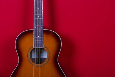 Kırmızı duvar arka planında altı telli halk akustik gitarı..