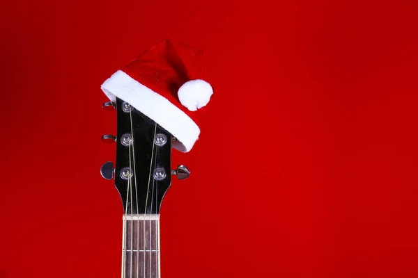 Concepto de música navideña. Guitarra acústica con cuerdas de acero y sombrero de Santa Claus . —  Fotos de Stock